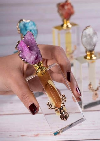 يد بنت تمسك بزجاجة مسك عليها علامة غزال من متجر مسك عاج الغزال