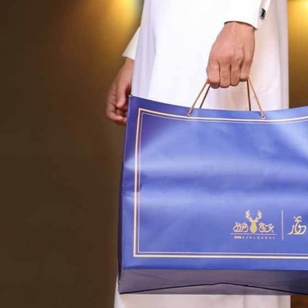 حيبة تسوق زرقاء من متجر هدايا عود عاج الغزال في يد رجل سعودي يليس ثوب