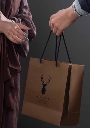 كيس هدايا بخور صغير بلون بني في يد بنت سعوديه من متجر بخور عاج الغزال