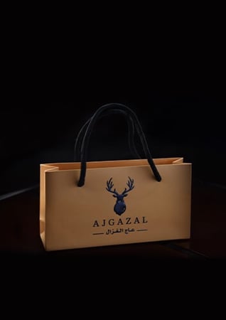 كيس هدايا توزيعات بني صغير عليه شعار غزال من متجر عاج الغزال