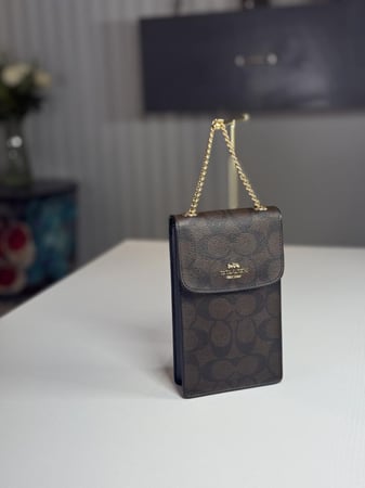 شنطة كوتش هاتف لميتد بلون بني سجنشر واسود NORTH/SOUTH PHONE CROSSBODY IN SIGNATURE CANVAS