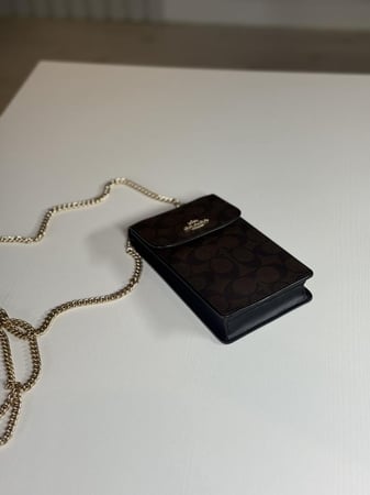 شنطة كوتش هاتف لميتد بلون بني سجنشر واسود NORTH/SOUTH PHONE CROSSBODY IN SIGNATURE CANVAS