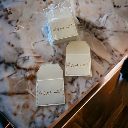 جيوب جلد أبيض بعبارة ألف مبروك12 حبه.