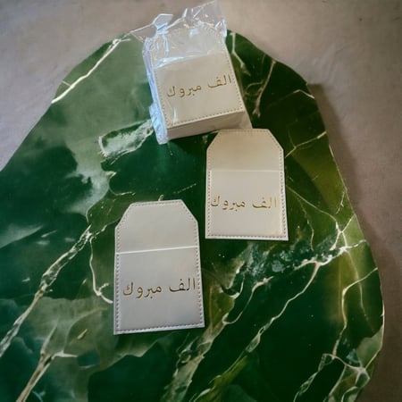جيوب جلد أبيض بعبارة ألف مبروك12 حبه.