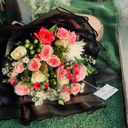 باقة ورد وردي وكريمي بتغليف أسود فاخر مع أزهار بيضاء