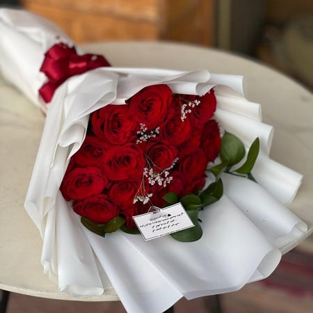 باقة همسة الحب من ورد جوري أحمر بتغليف أبيض وربطة حمراء