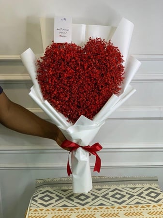 باقة ورد حمراء على شكل قلب بتغليف أبيض أنيق