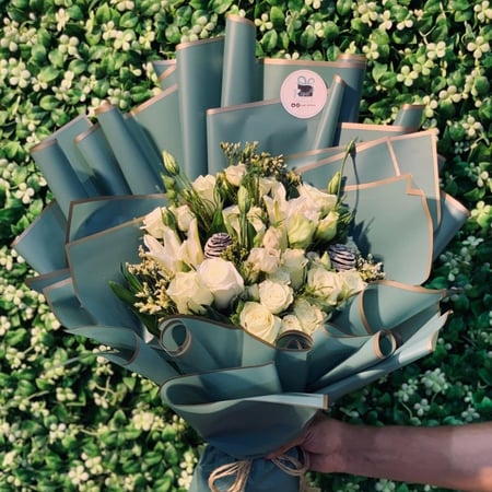 باقة ورد أبيض فاخرة بتغليف أخضر بحواف ذهبية أنيقة