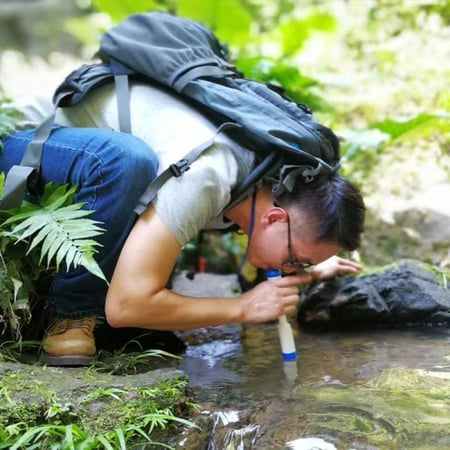 person drinking from the purifier in a river