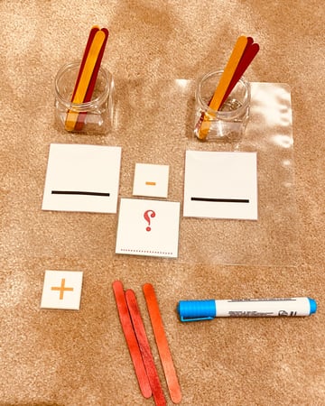 نشاط تعليمي لمفهومي الجمع والطرح معًا ( مقاس A4 ) طباعة ليزر ومغلفة حراريًا للحماية والكتابة والمسح عليها ، عبارة عن خانتين للأرقام + علامتي الجمع والطرح مزودة بشك شاك + علبتين بلاستيكية و 20 حبة من أعواد الايسكريم الملونة للعد + قلم سبورة