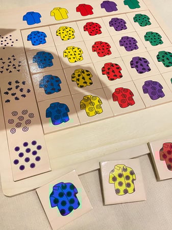 لعبة القمصان الملونة الخشبية لمفهوم النمط مناسبه لتنمية المهارات البصرية والإدراكية عبارة عن قاعدة خشبية متينة مزودة بقطعتين كبيرة واكثر من عشرون قطعة خشبية صغيرة