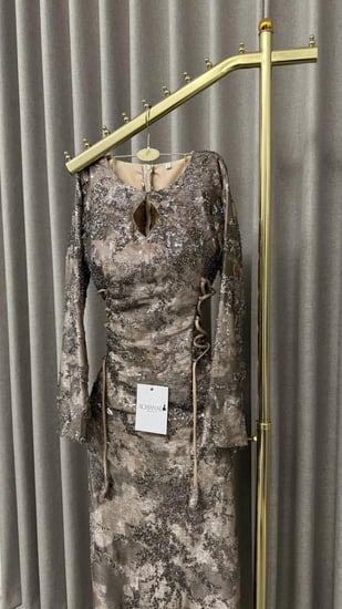 فستان سهرة طويل بأكمام وفتحة صدر بنقشة معدنية وأربطة جانبية.