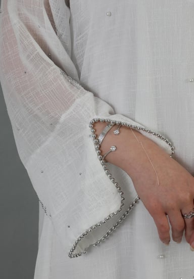 فستان صيفي أبيض بأكمام طويلة شفافة مزين بنقشة وياقة v