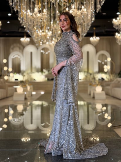 فستان سهرة تستحقّين فستانًا يلمع بقدرك هذا السيلفر المطرّز بالكامل برقبة عالية وأكمام كاب متدفّقة صُمّم ليبرز جمالك برقيّ