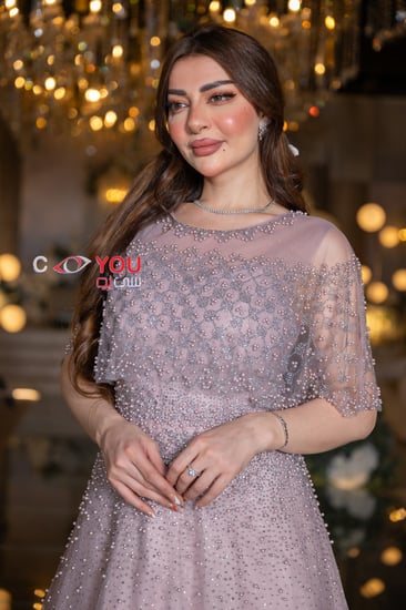 فستان سهرة وردي مطرز بخرز ناعم مع كاب شفاف قصير يضفي لمسة أنثوية حالمة، مثالي للخطوبة والمناسبات الفاخرة.