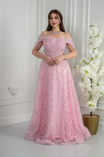 فستان سهرة وردي أوف شولدر يفيض أنوثة ورقّة. دانتيل مطرّز بلمعة ناعمة يلتقط الضوء برهافة