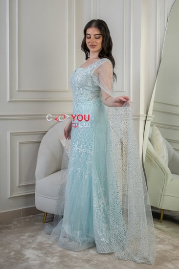 فستان سهرة سماوي مطرّز بقصّة عمودية ورقبة مربعة مع كاب شفاف مرصّع.