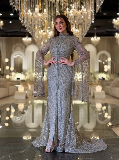 فستان سهرة تستحقّين فستانًا يلمع بقدرك هذا السيلفر المطرّز بالكامل برقبة عالية وأكمام كاب متدفّقة صُمّم ليبرز جمالك برقيّ
