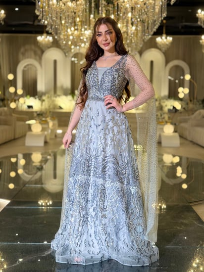 فستان سهرة فضي لامع بقصة وكاب شفاف فاخر وأكمام منسدلة يسرق الأنظار في كل مناسبة