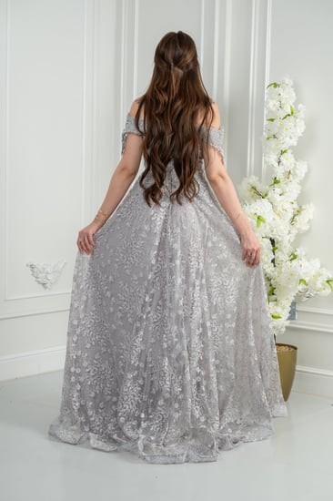 فستان سهرة فضّي أوف شولدر بلمعة راقية يوازن بين النعومة والحضور.