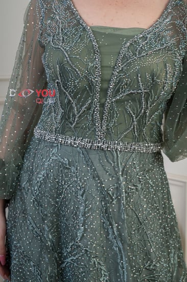 فستان سهرة فاخر مطرز بأكمام طويلة بلون أخضر زمردي.