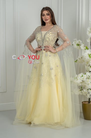 فستان سهرة أصفر باستيل مطرز بالترتر مع أكمام شفافة طويلة