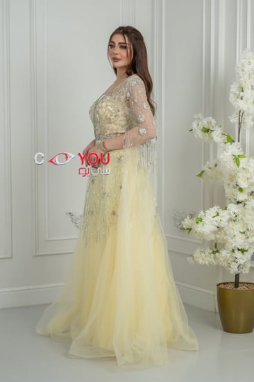 فستان سهرة أصفر باستيل مطرز بالترتر مع أكمام شفافة طويلة