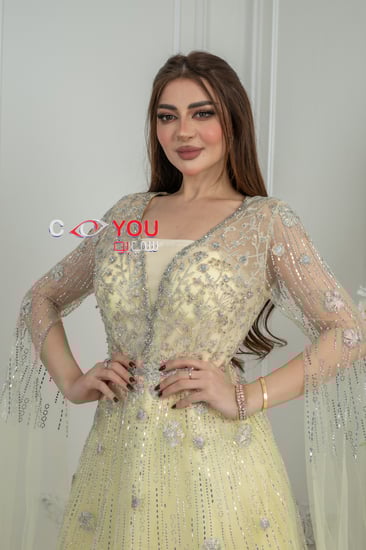 فستان سهرة أصفر باستيل مطرز بالترتر مع أكمام شفافة طويلة