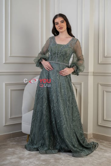 فستان سهرة فاخر مطرز بأكمام طويلة بلون أخضر زمردي.