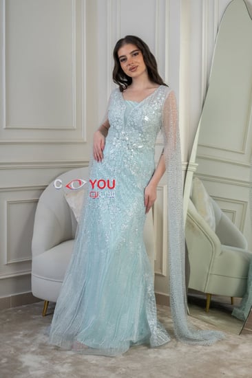 فستان سهرة سماوي مطرّز بقصّة عمودية ورقبة مربعة مع كاب شفاف مرصّع.