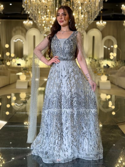 فستان سهرة فضي لامع بقصة وكاب شفاف فاخر وأكمام منسدلة يسرق الأنظار في كل مناسبة