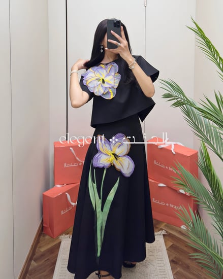 تفصيل أنثوي لوردة بنفسجية على بلوزة سوداء أنيقة