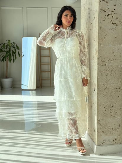 فستان دانتيل أبيض أنيق بتفاصيل شفافة وقصة عصرية