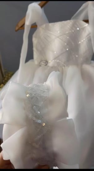 فستان ابيض انيق مزين بالتطريز الترتر على الصدر مع شرايط على الكتف مع وشاح تطريز