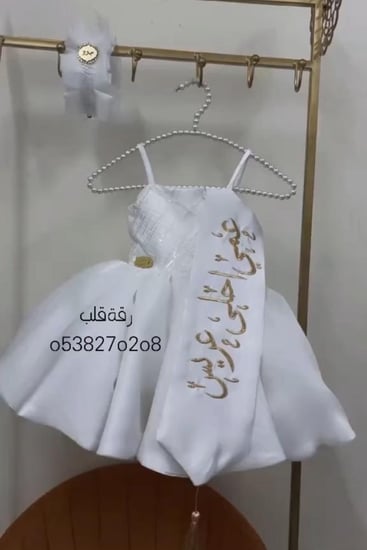 فستان ابيض انيق مزين بالتطريز الترتر على الصدر مع شرايط على الكتف مع وشاح تطريز