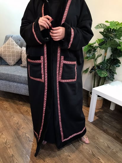 فروة سوداء شتوية نسائية تظهر تصميمها الأنيق مع أطراف حمراء منقوشة