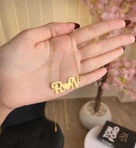 عقد يجمع-حرفين في بريق الذهب عيار 21.