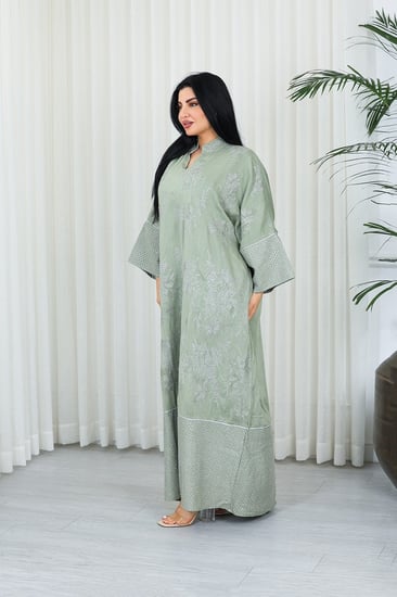 جلابية قماش بطول يصل للكاحل بنهايات أكمام واسعة وياقة صغيرة مزينة بالتطريزات والترتر على كامل القماش الأمامي