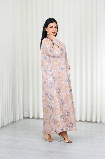 جلابية قماش بطول يصل للكاحل بأكمام واسعة متوسطة الطول وياقة صغيرة مزينة بالتطريزات موردة بشكل دائري على كامل القماش