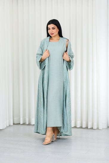 جلابية قماش بطول يصل للكاحل مكونة من قطعة سادة وقطعة مزينة بالتطريزات البارزة على كامل القماش