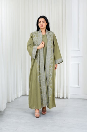 جلابية قماش بطول يصل للكاحل مكونة من قطعة سادة وقطعة مزينة بالترتر اللامع على أطراف الأكمام وعلى طول الجلابية الخارجي ومنتصف الظهر