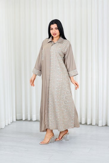 جلابية قماش بطول يصل للكاحل بأزرار مخفية وياقة بأكمام مطوية مزينة بتطريزات بنهاية الأكمام وعلى جانب الجلابية مزودة بجيبة على الصدر