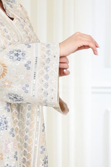 جلابية قماش بطول يصل للكاحل بأكمام واسعة متوسطة الطول وياقة صغيرة مزينة بالتطريزات موردة بشكل دائري على كامل القماش