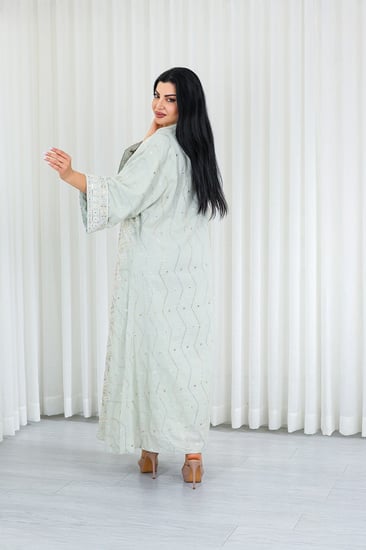 جلابية قماش بطول يصل للكاحل بأكمام واسعة متوسطة الطول وياقة صغيرة مزينة بالترتر اللامع وبالتطريزات على كامل القماش