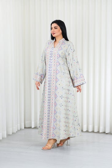 جلابية قماش بطول يصل للكاحل بأكمام بنهايات واسعة وياقة مزينة بالترتر وبالتطريزات البارزة على كامل القماش