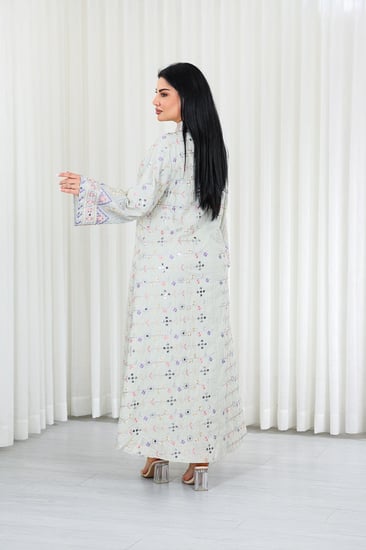 جلابية قماش بطول يصل للكاحل بأكمام بنهايات واسعة وياقة مزينة بالترتر وبالتطريزات البارزة على كامل القماش