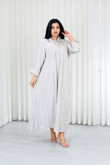 جلابية قماش بطول يصل للكاحل بأزرار مخفية وياقة بأكمام مطوية مزينة بتطريزات بنهاية الأكمام وعلى جانب الجلابية مزودة بجيبة على الصدر