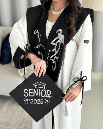 عباية تخرج 2025 لون أبيض مع وشاح وقبوع باللون الأسود