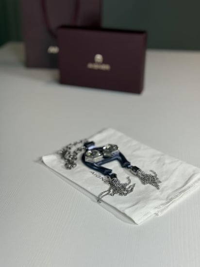 تعليقة اجنر باللون الازرق المعدني اللامع على شكل حذوه من الجلد الوردي Aigner metallic blue charm with stones and tassel's