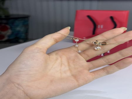 اسوار كارولينا مزين على شكل باو ذهبي مع لولو متدلي carolina Herrera gold bow pearl bracelet